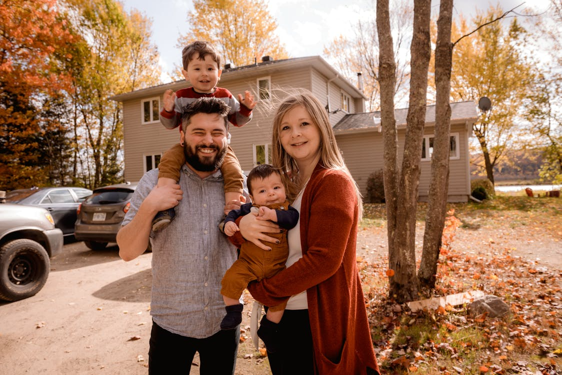 Family smiling together in front of their home